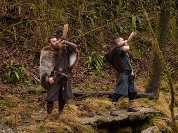 Men wearing costume standing on rock in forest