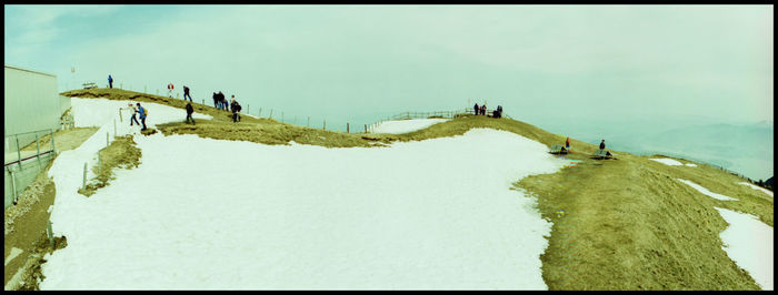 People on snow covered landscape against sky