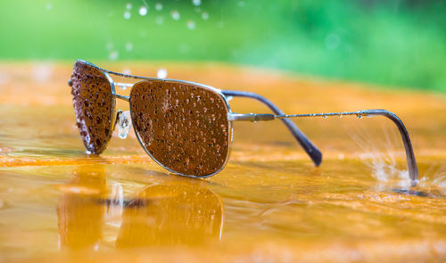 A pair of sunglasses is on a table in rainy weather