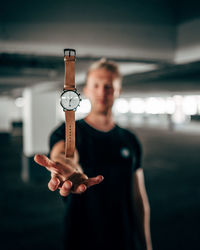 Young man holding camera while standing outdoors