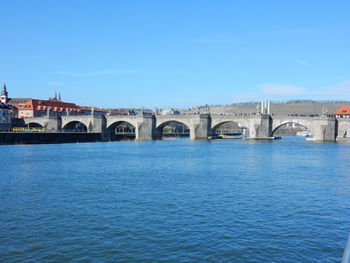 Arch bridge over river against blue sky