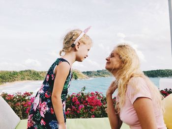 Side view of mother and daughter looking each other face to face by sea