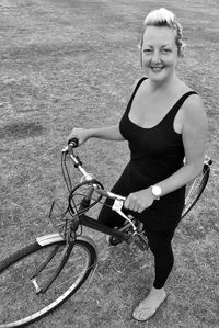 Portrait of smiling mature woman with bicycle on field