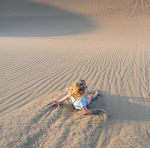 High angle view of girl sliding on sand dune