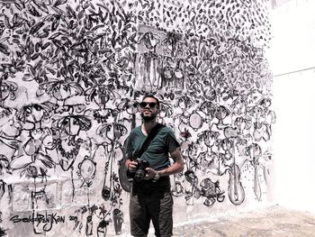 Portrait of young man standing against wall