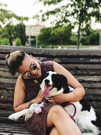 Smiling young woman sitting with border collie at park