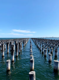 Wooden posts in sea against clear sky