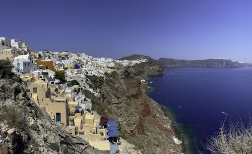 High angle view of townscape by sea against clear blue sky