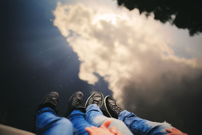 Low section of couple sitting by lake