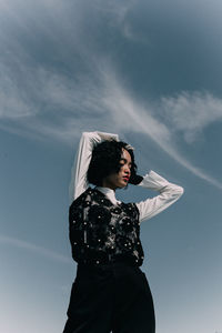 Young woman standing against sky