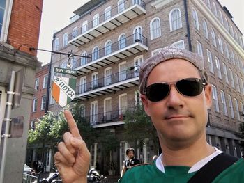 Portrait of man wearing sunglasses against buildings in city