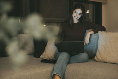 Portrait of woman sitting on sofa at home