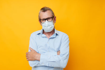 Young man wearing sunglasses while standing against yellow background