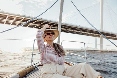 Senior woman sitting on boat against sea