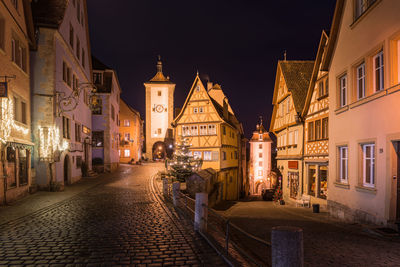 Illuminated street amidst buildings in city at night