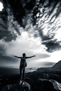 Rear view of man standing on rock against sky