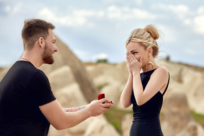 Young woman using mobile phone against sky