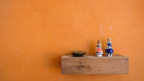 Close-up of bottles on table against orange wall