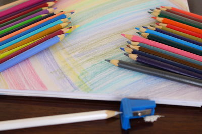 Close-up of colored pencils on book at table