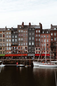 Buildings by river against sky in city