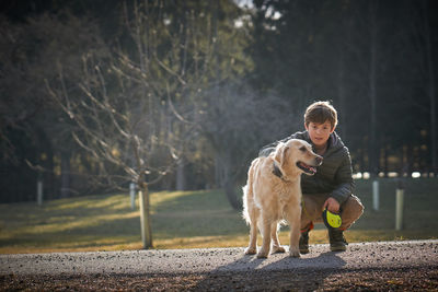 Full length portrait of boy with dog at park