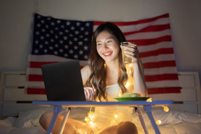 Young woman using phone while sitting on table