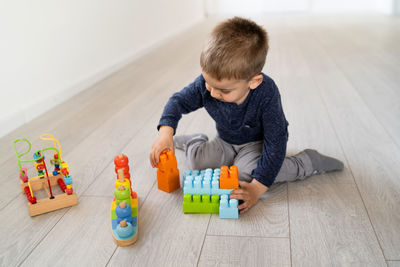 Boy playing with toy sitting on floor at home