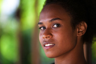 Close-up portrait of smiling young woman looking away