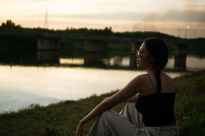 Woman looking away while sitting on land