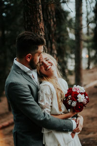 Couple with bouquet embracing in woodland