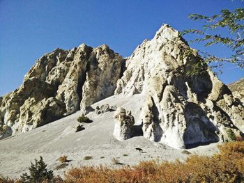 Low angle view of rock formations against clear blue sky