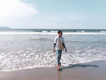 Full length of boy on beach against sky