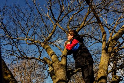 Boy standing by bare trees