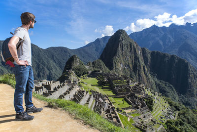 Man standing looking away at view of inca ruins, machu picchu, peru