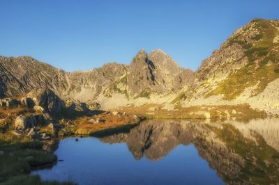 Scenic view of lake and mountains against clear blue sky