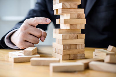 Midsection of businessman playing block removal game on desk in office