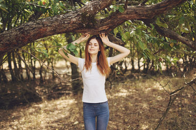 Portrait of smiling young woman standing on tree