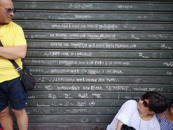 Rear view of friends looking up while standing against shutter