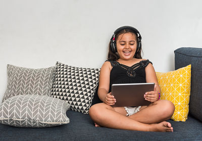 Young woman using mobile phone while sitting on laptop