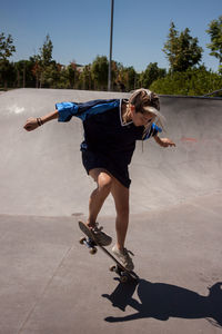 Full length of woman skateboarding at skateboard park