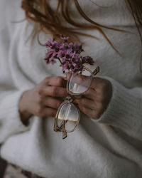 Midsection of woman holding purple flowers and eyeglasses