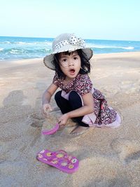 Portrait of girl playing with sand at beach