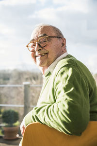 Portrait of smiling senior man sitting on chair at the window