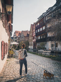 Rear view of woman walking on footpath by buildings in city