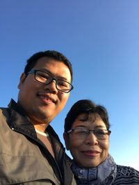 Portrait of mother and son against clear blue sky