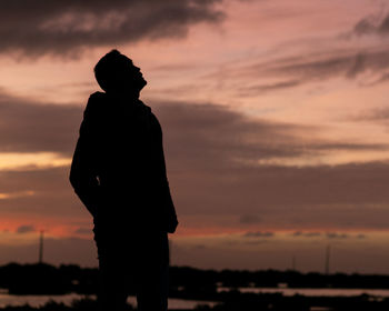 Rear view of silhouette man standing against sky during sunset