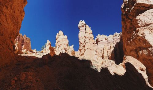 Low angle view of rocky mountain against blue sky