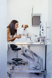 Smiling veterinarian holding dog on table in animal hospital