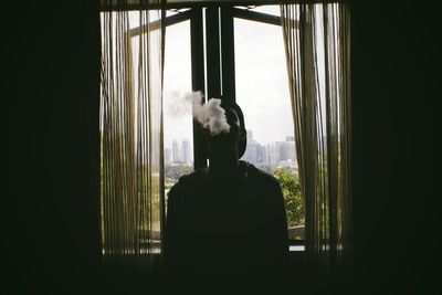 Rear view of man looking through window