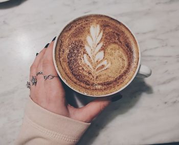 High angle view of woman holding coffee cup on table